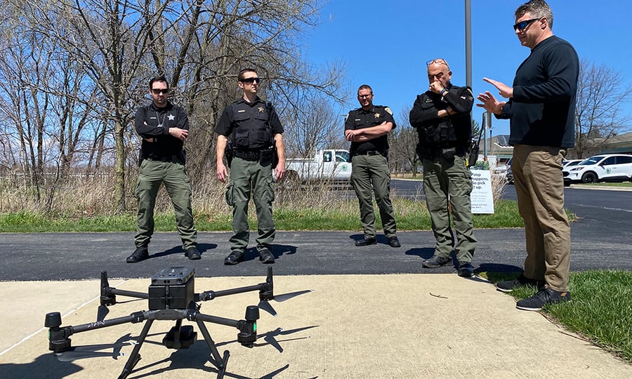 Police officers circle a grounded drone.