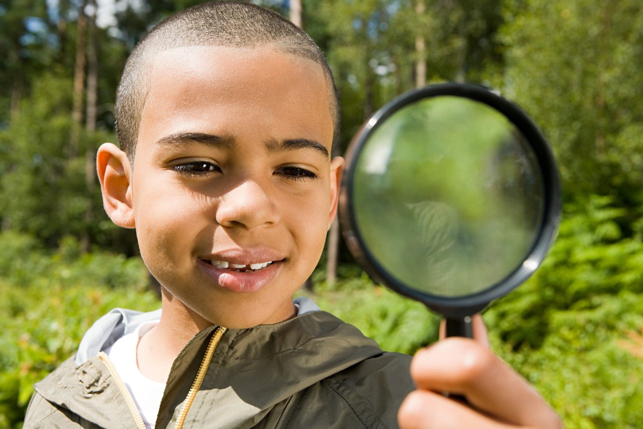 boy in nature using a magnifying glass