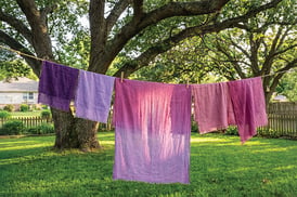 Dyed fabrics dry on a clothesline.