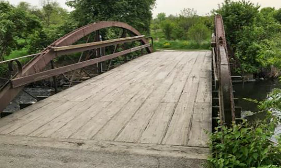 A side view of the wood and cast iron bridge that spans the East Branch DuPage River.
