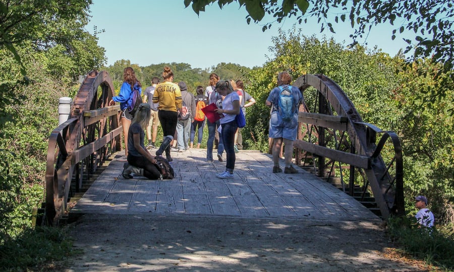 A group of students stand on the old bridge.