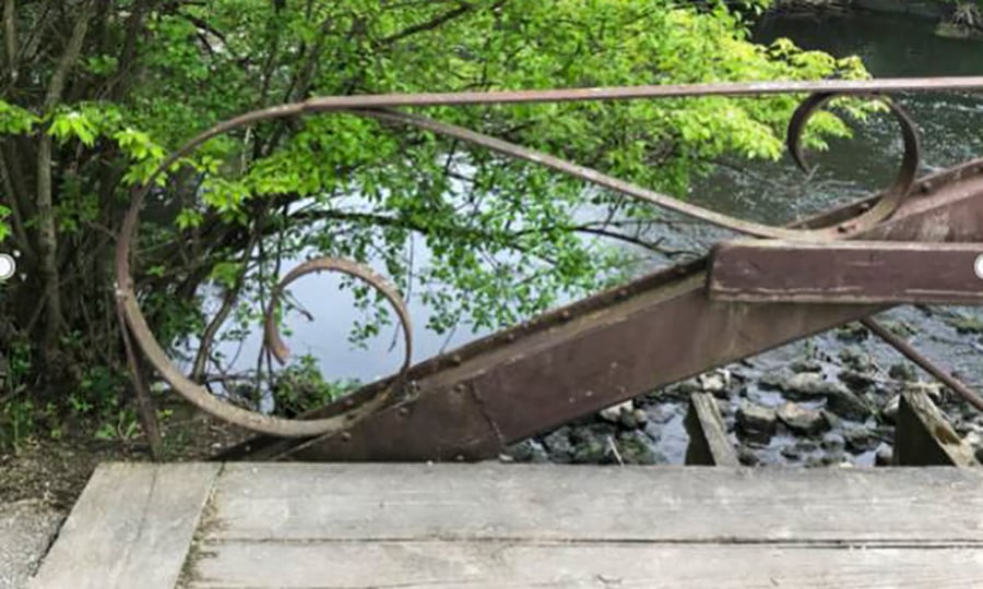 Iron is curved to form a decorative handrail near the end of the bridge.