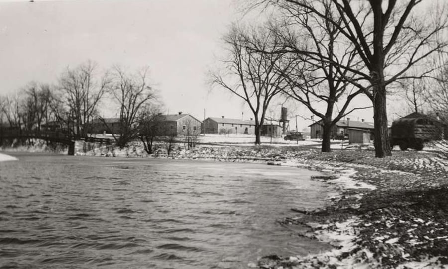 A 1937 photo showing a shoreline, military transport vehicle and buildings in the distance.