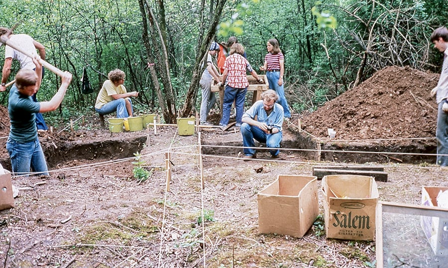 Students extract dirt and artifacts at a dig site.