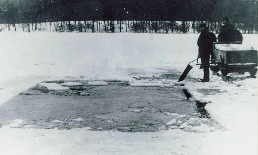 Two men stand on a frozen and snow-covered Salt Creek during an ice cutting session.