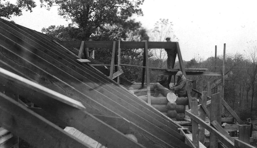 A zoomed-out version of the man chiseling a log.