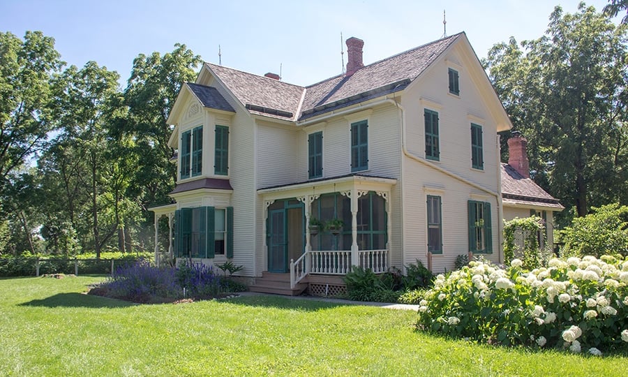 A farmhouse with newly-installed finials is photographed on a sunny afternoon.