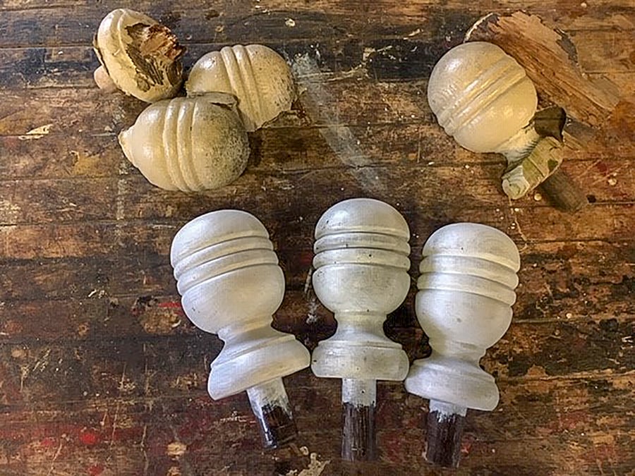 Freshly crafted newel post finials rest beside broken old ones.