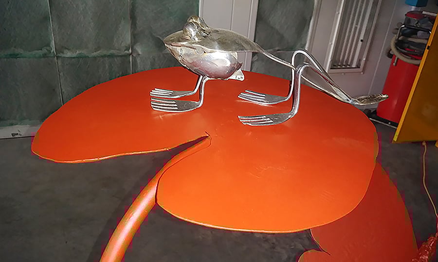 A metallic frog is partially constructed from forks and spoons.