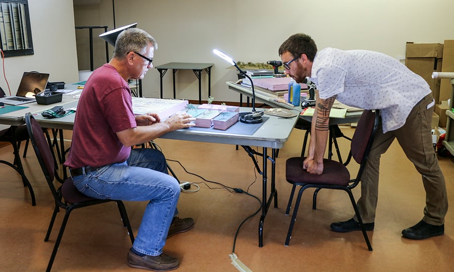 Two men work on the model in a studio.