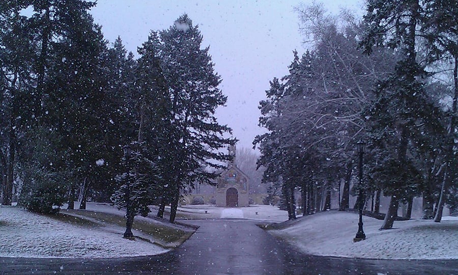 The drive at an estate leading to a chapel as snow falls.