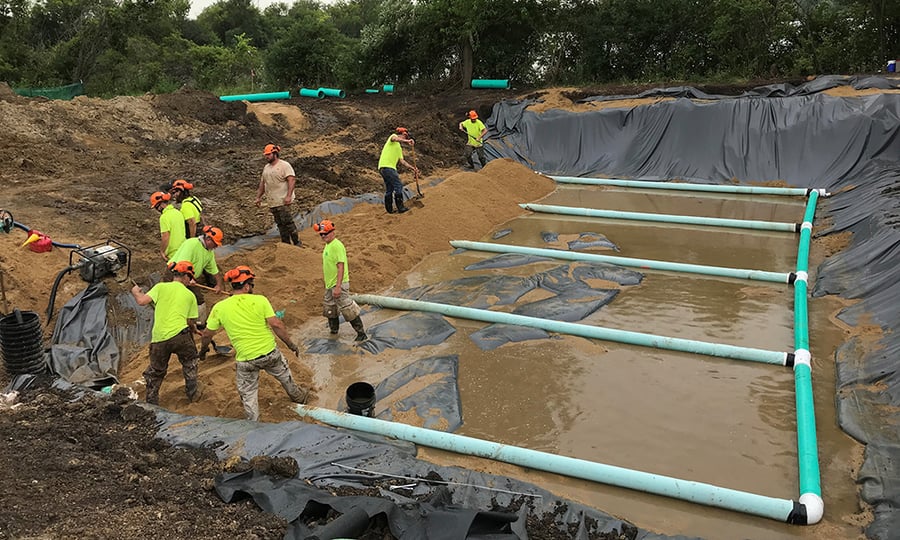 A crew continues to work on the filtration system with hand tools.