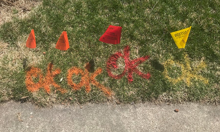 Small orange, red, and yellow flags mark utility lines.