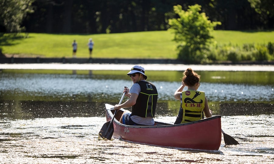 Two people paddle a red canoe across a lake.