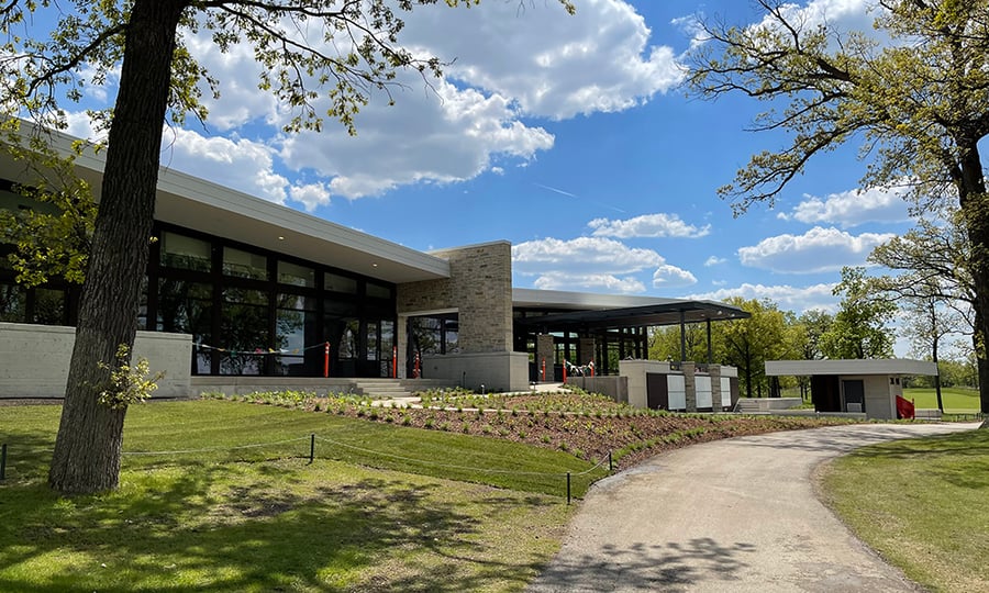 A modern clubhouse surrounded by native plants.