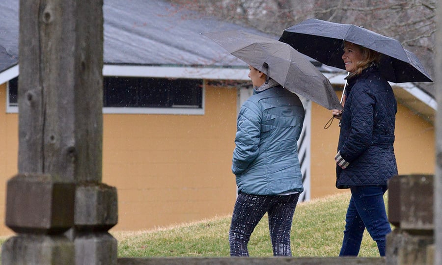 Two women walk in the rain holding umbrellas.