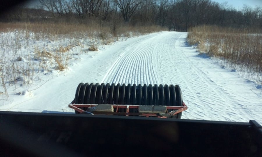 A groomer lays fresh corduroy on a trail.