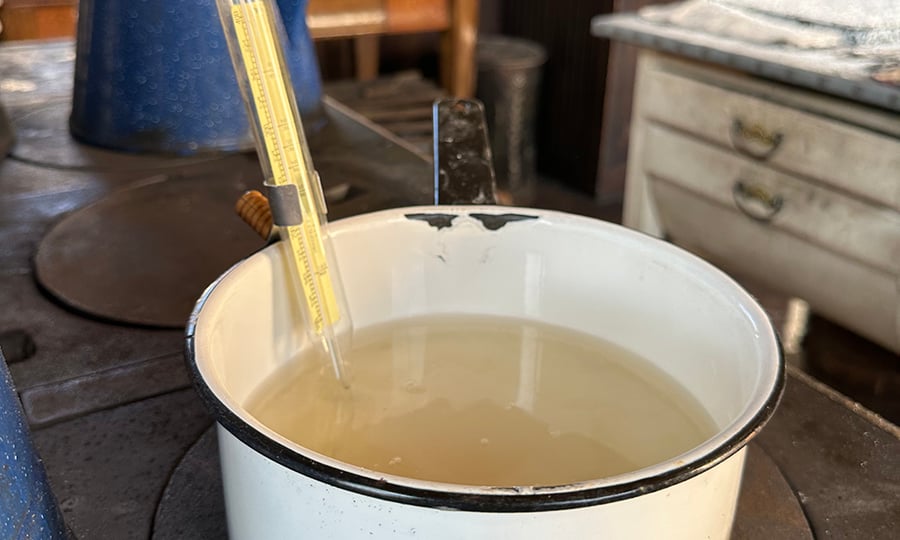 A thermometer rests in a pot on a stove.
