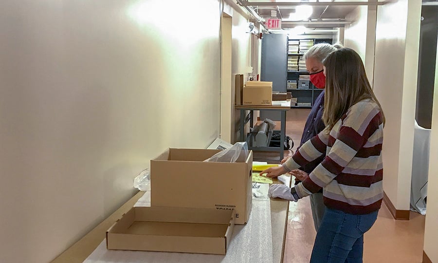 Two women categorize historic artifacts.