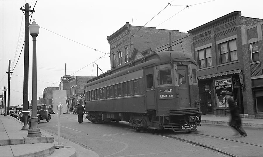 A single train car in the middle of a town street.