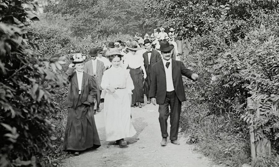 An old photograph of people on a hiking trail.
