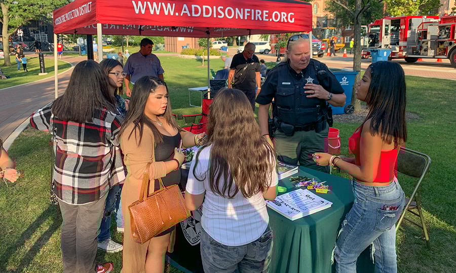 A female police officer chats with a group of girls during a community event.