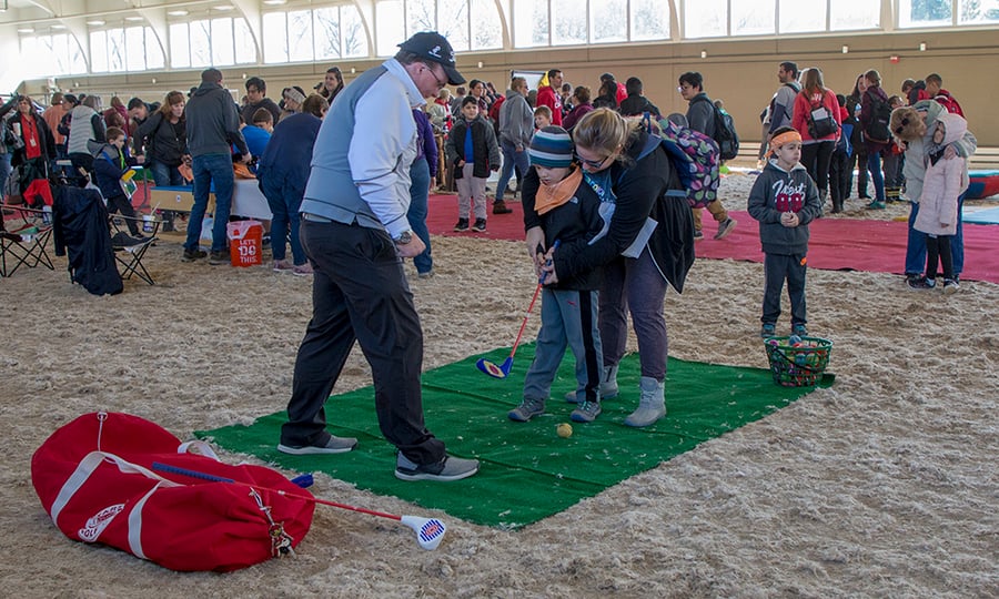 A boy gets a lesson on how to hit a golf ball.
