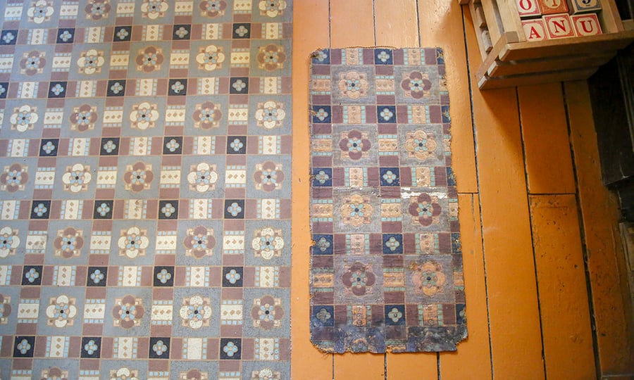 A scrap of an original oilcloth from from the 1800s lies next to a reproduction with a similar design.
