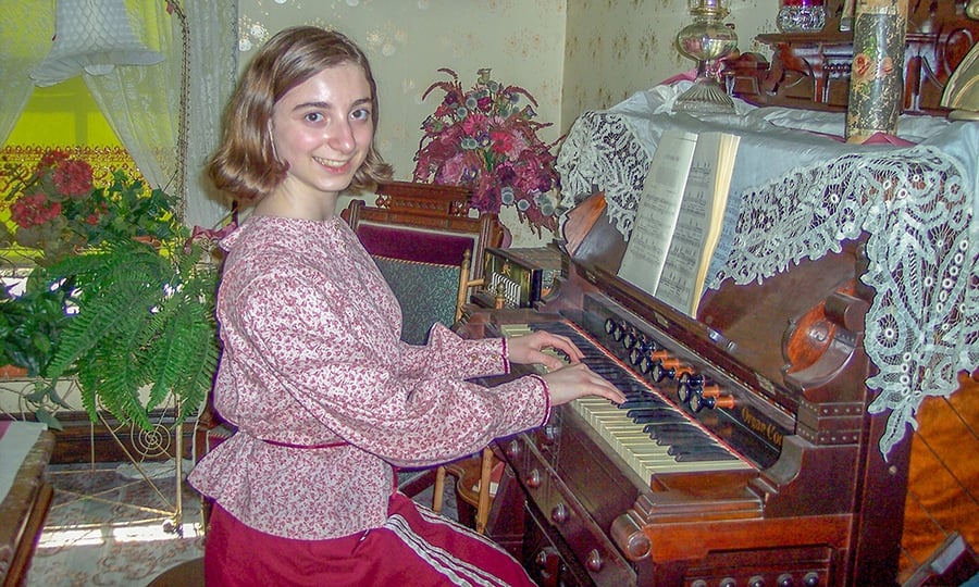 A woman sits and plays the old pipe organ.