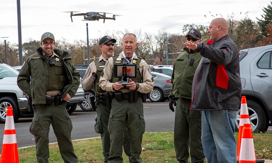 Another officer flies the drone at just above head height.