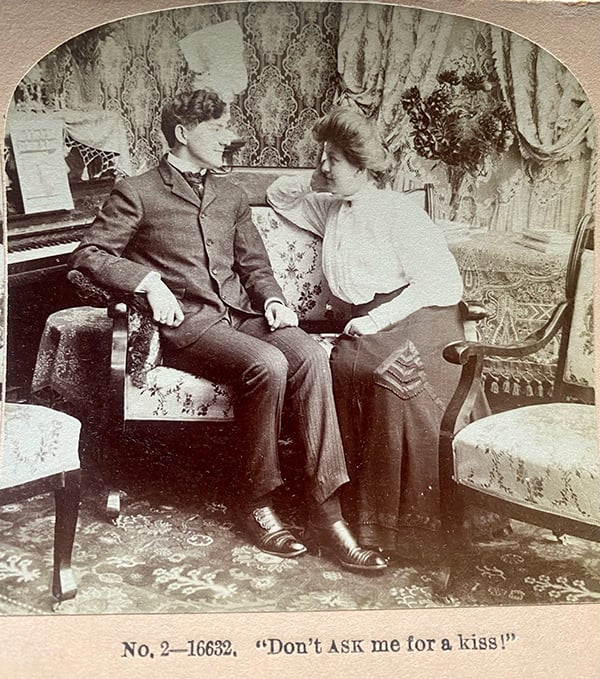 A man and a woman sit on a chair staring at each other in this old love-themed card.
