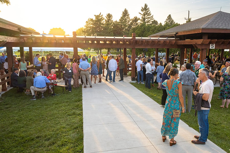 A group of sharp-dressed people stand outside during an event at sunset.