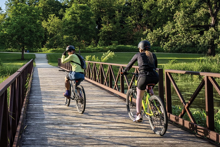 two women biking over a bridge on a trail two women biking over a bridge on a trail
