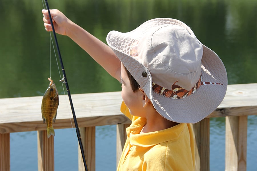 a boy holding a fishing pole with a fish on the end of the line