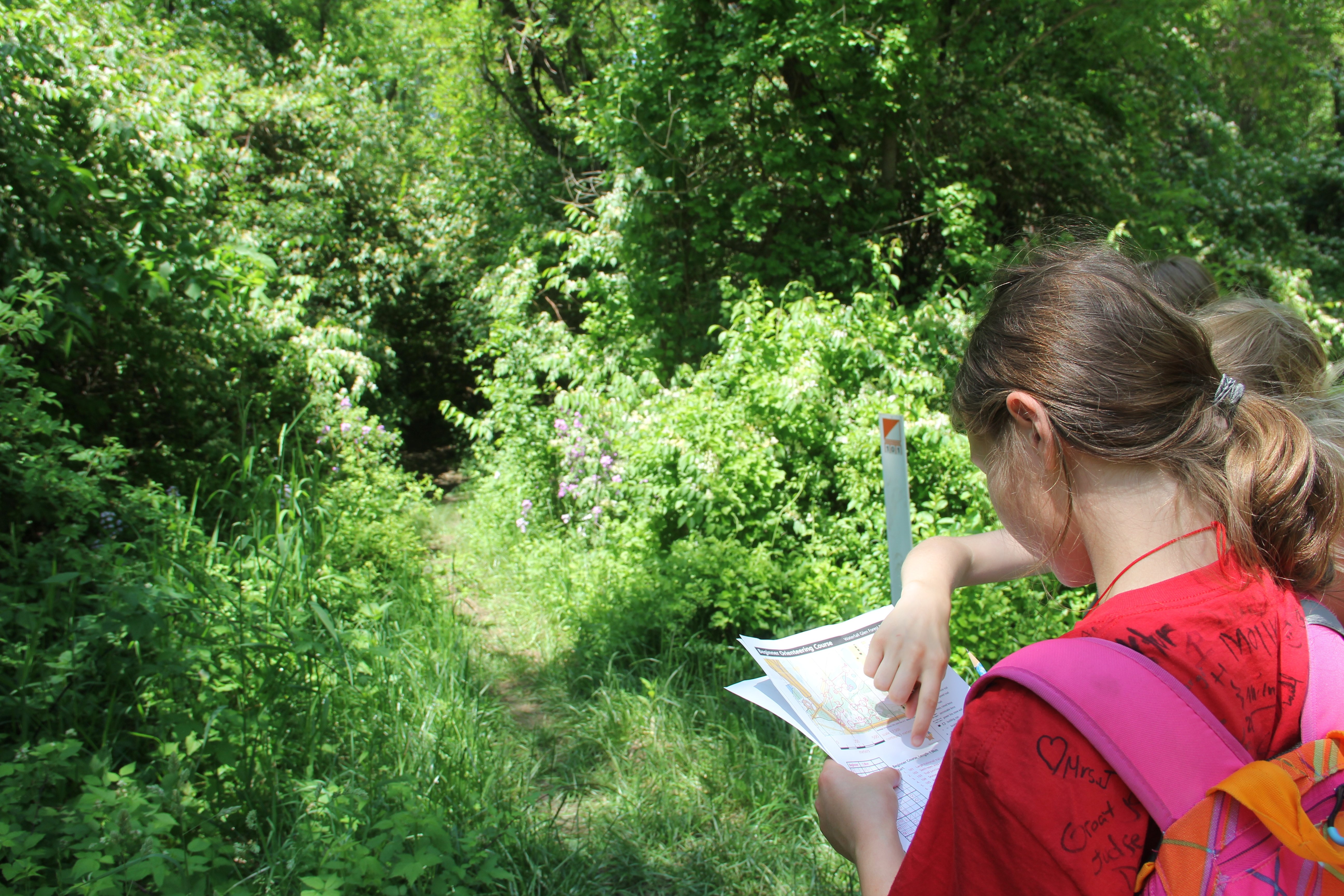 two girls reading an orienteering map in a forest preserve