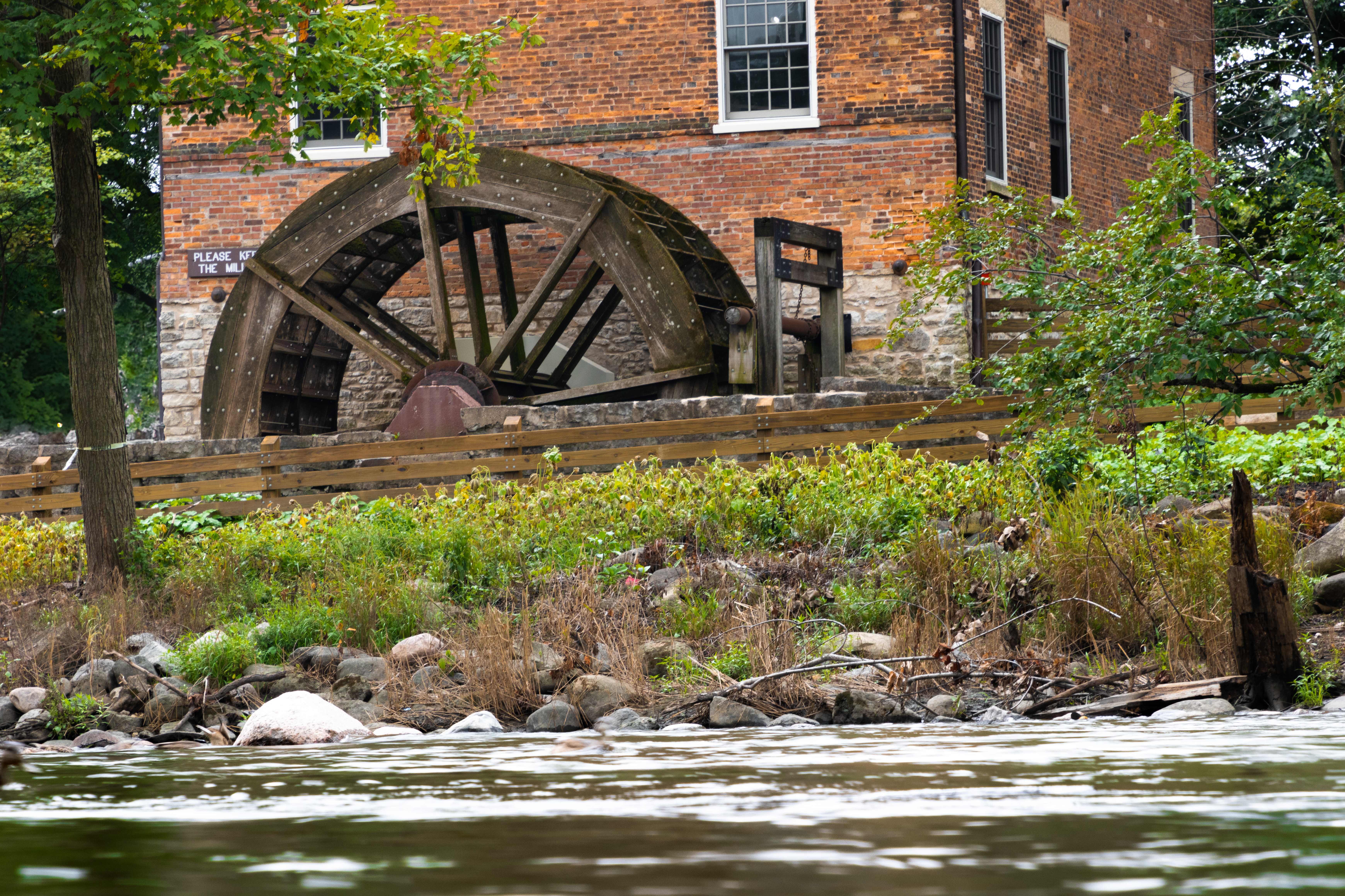 A grist mill with its wheel stand beside a creek.