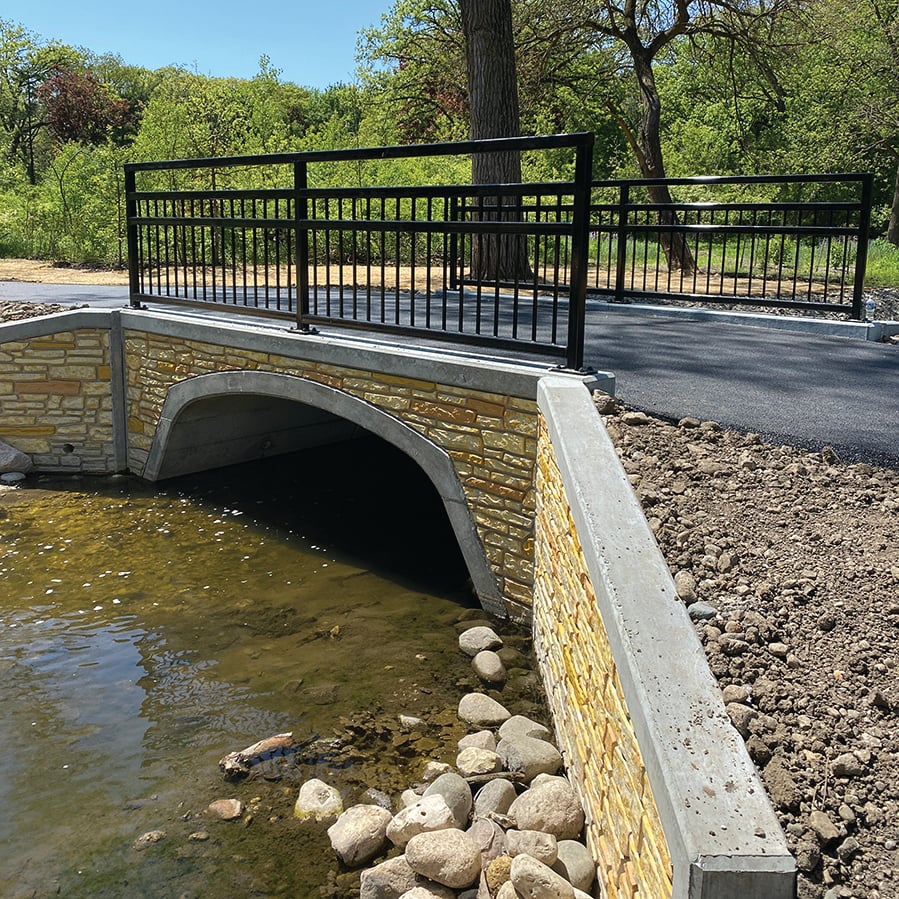 A paved bridge straddles a shallow creek.