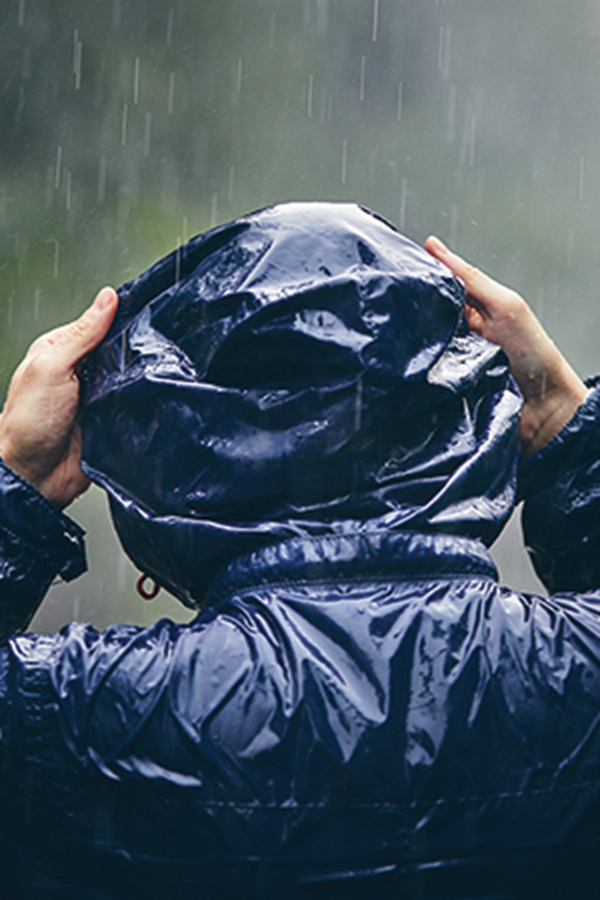 person wearing a raincoat and putting up the hood in the rain