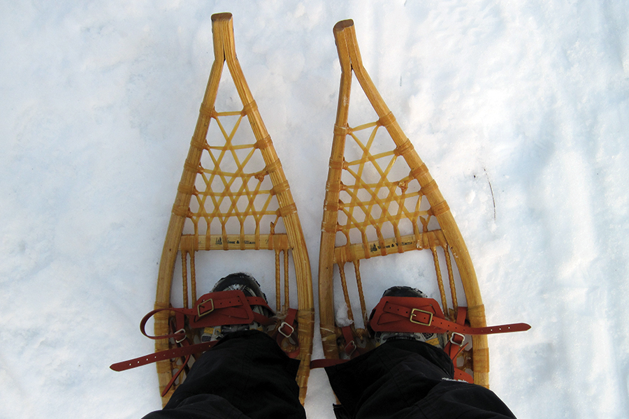 a person wearing a pair of Ojibwa snowshoes standing in the snow