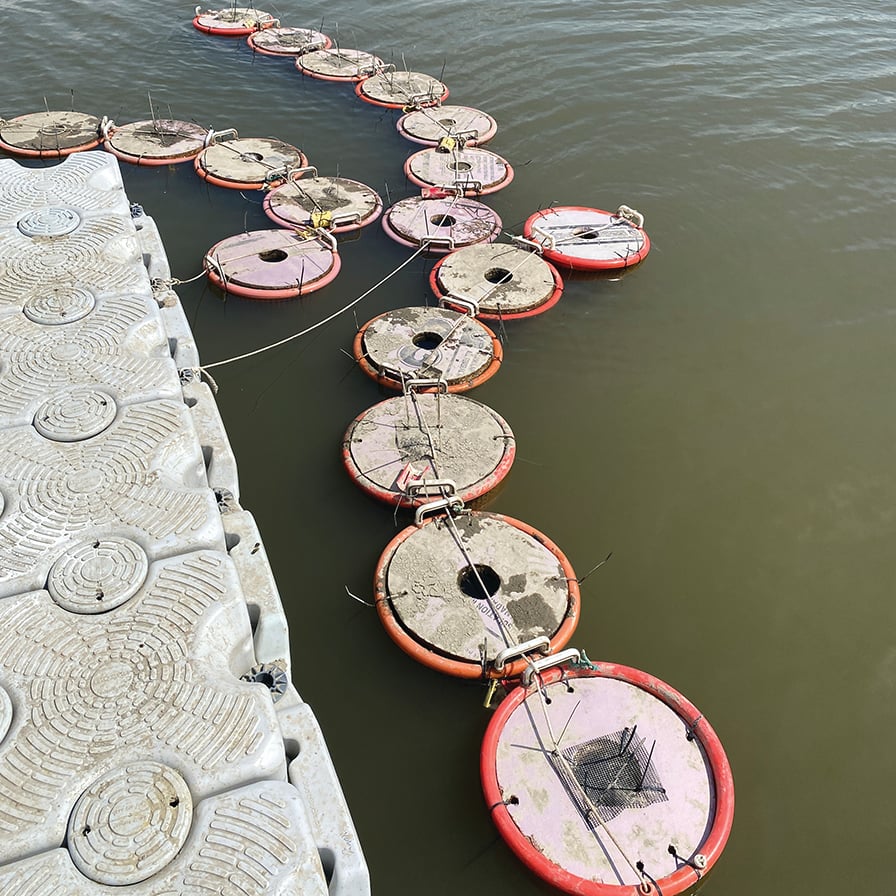Baskets float next to a dock on a lake.