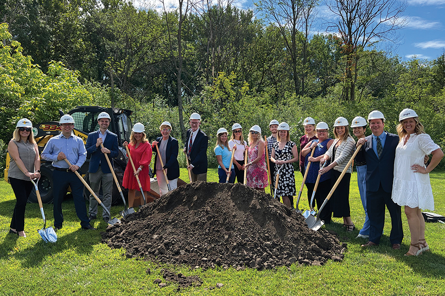 several people in hardhats holding shovel behind a pile of soil